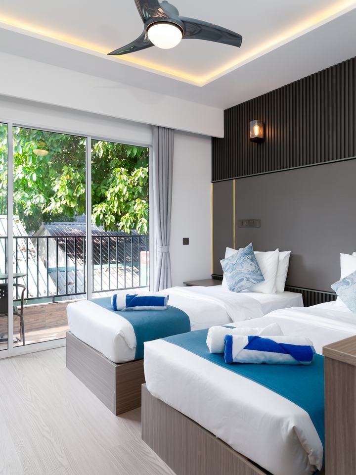 The room with twin beds turned down and the balcony doors open along one side.