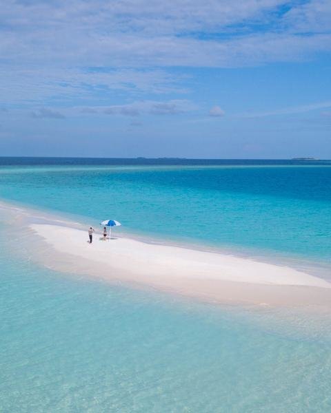 A sandbank standing above pale shallow water.