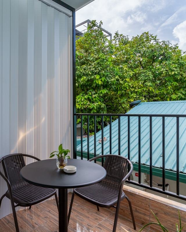 Two chairs and a small table on the private balcony, looking out over the treetops.