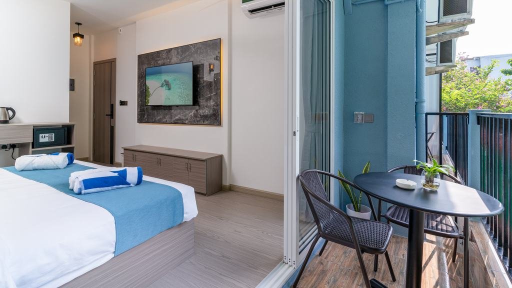 The room with the balcony door open, trees beyond it.