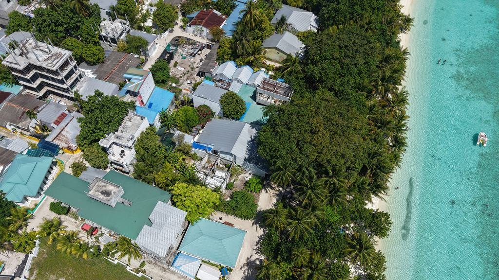 Ukulhas from above: rooftops, narrow streets and palms running down to the shoreline and the pale lagoon.